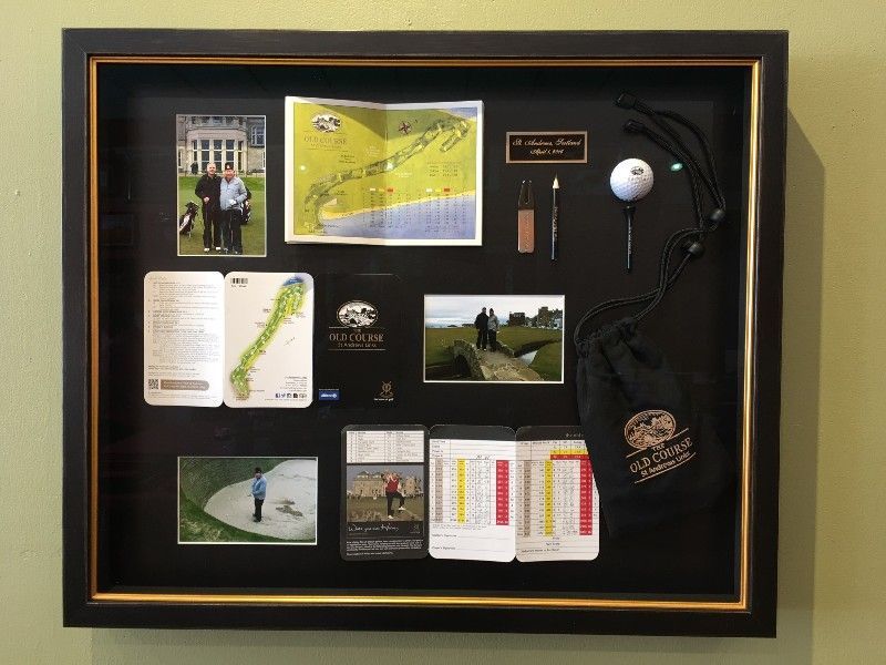 A framed display of golf memorabilia including a golf ball and gloves