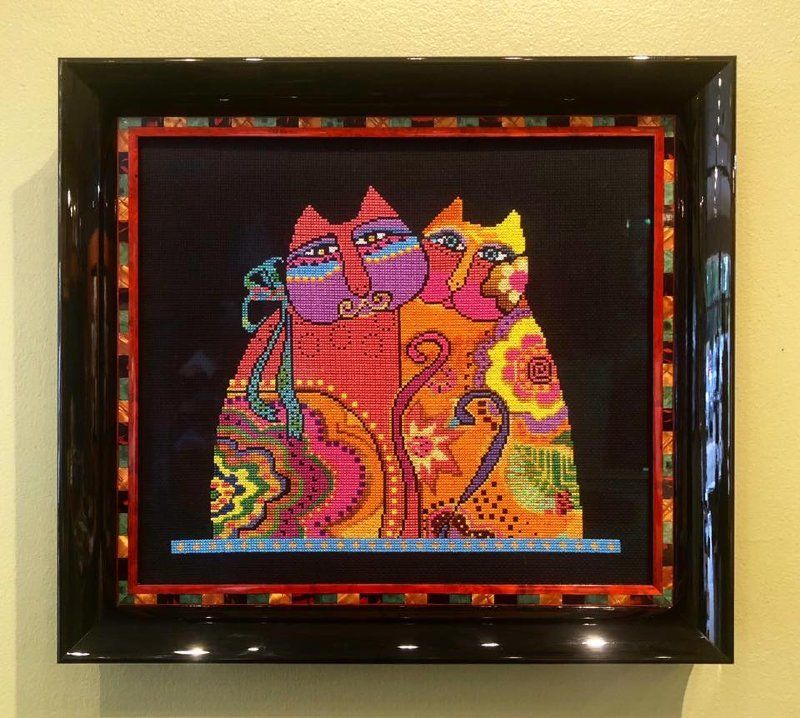 A framed painting of three colorful cats on a wall