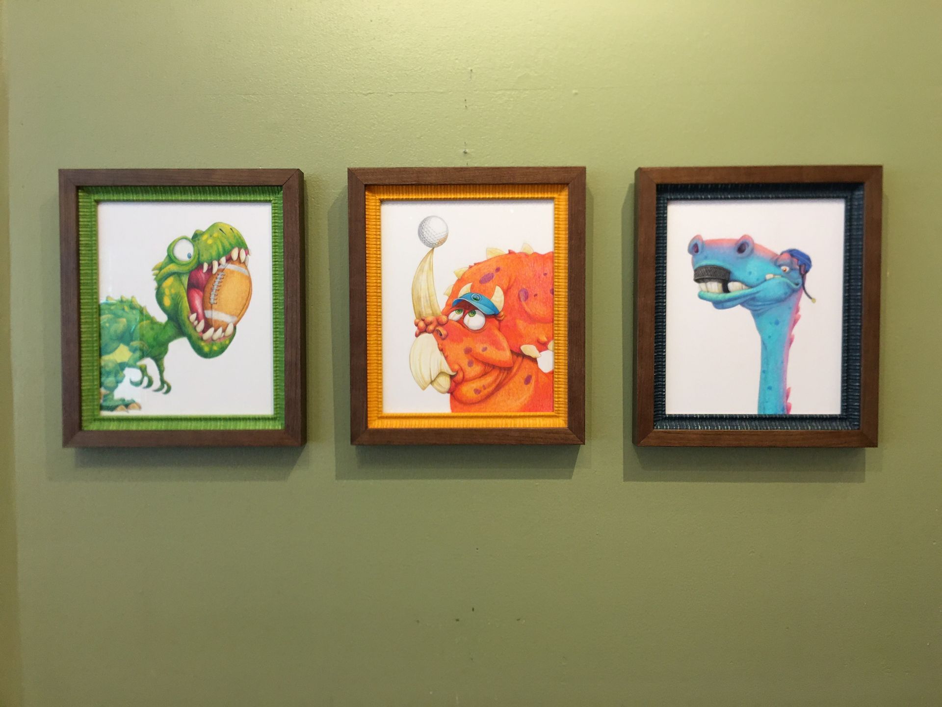 Three paintings of dinosaurs are hanging on a wall.
