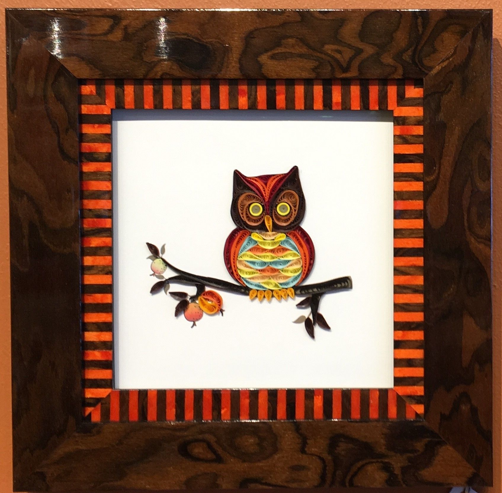 A framed picture of an owl sitting on a branch