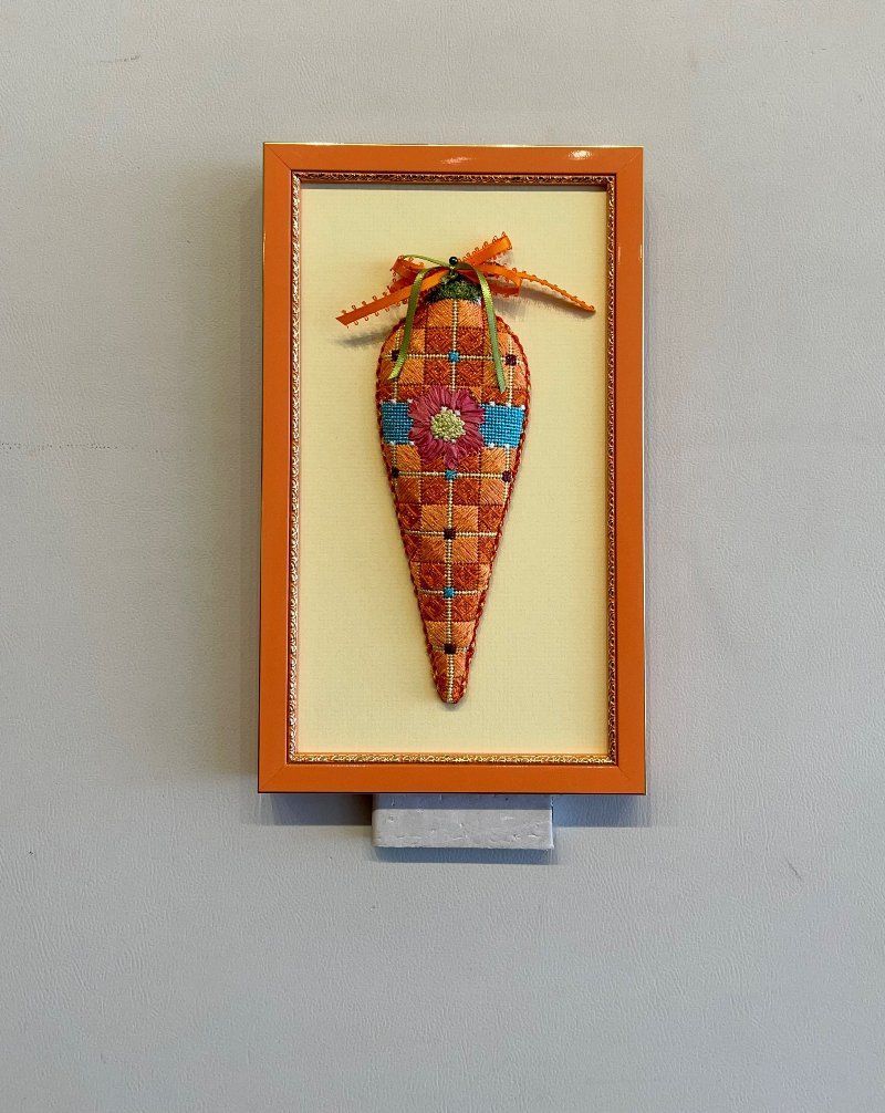 A picture of a carrot in a frame on a wall
