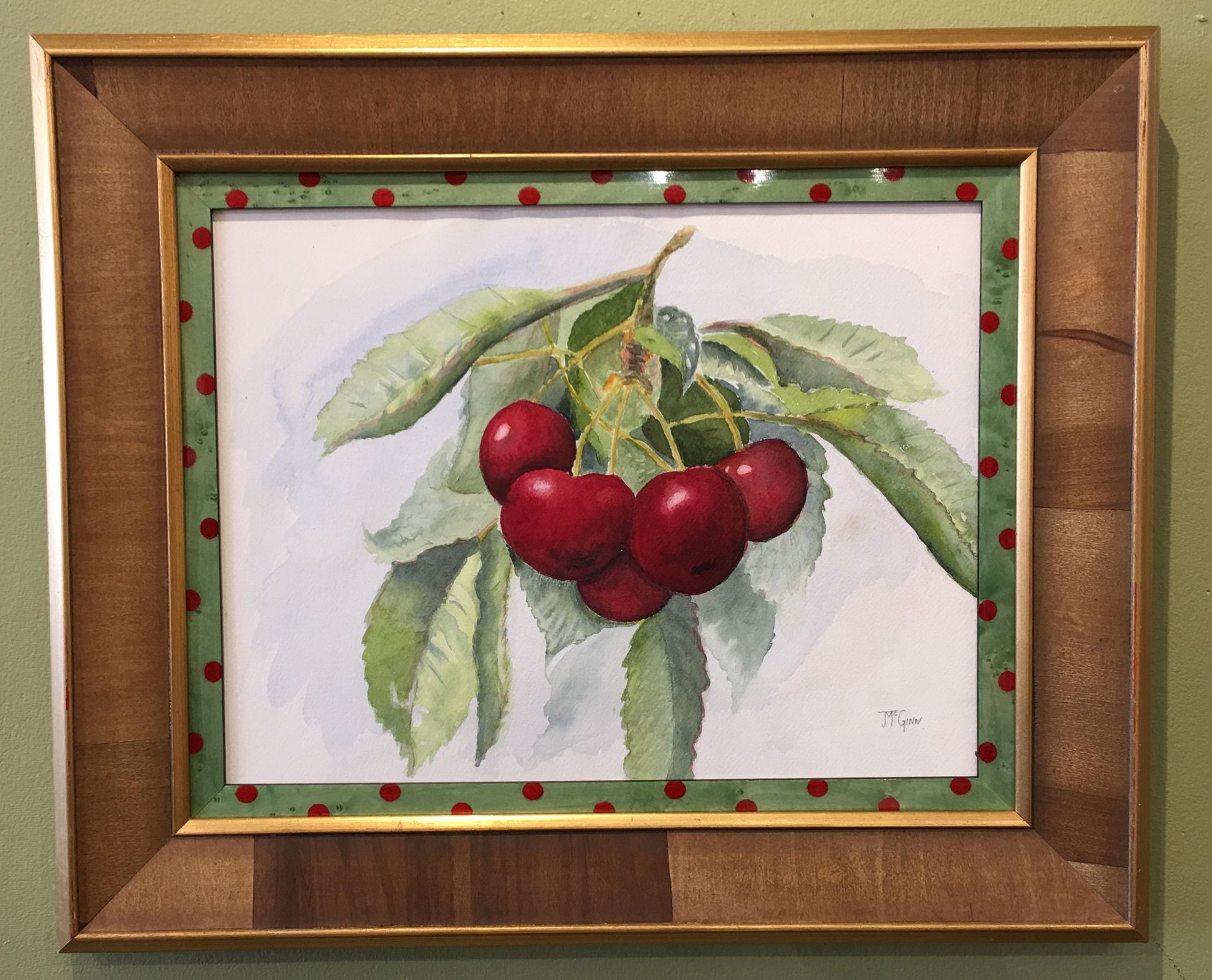 A framed painting of cherries on a tree branch