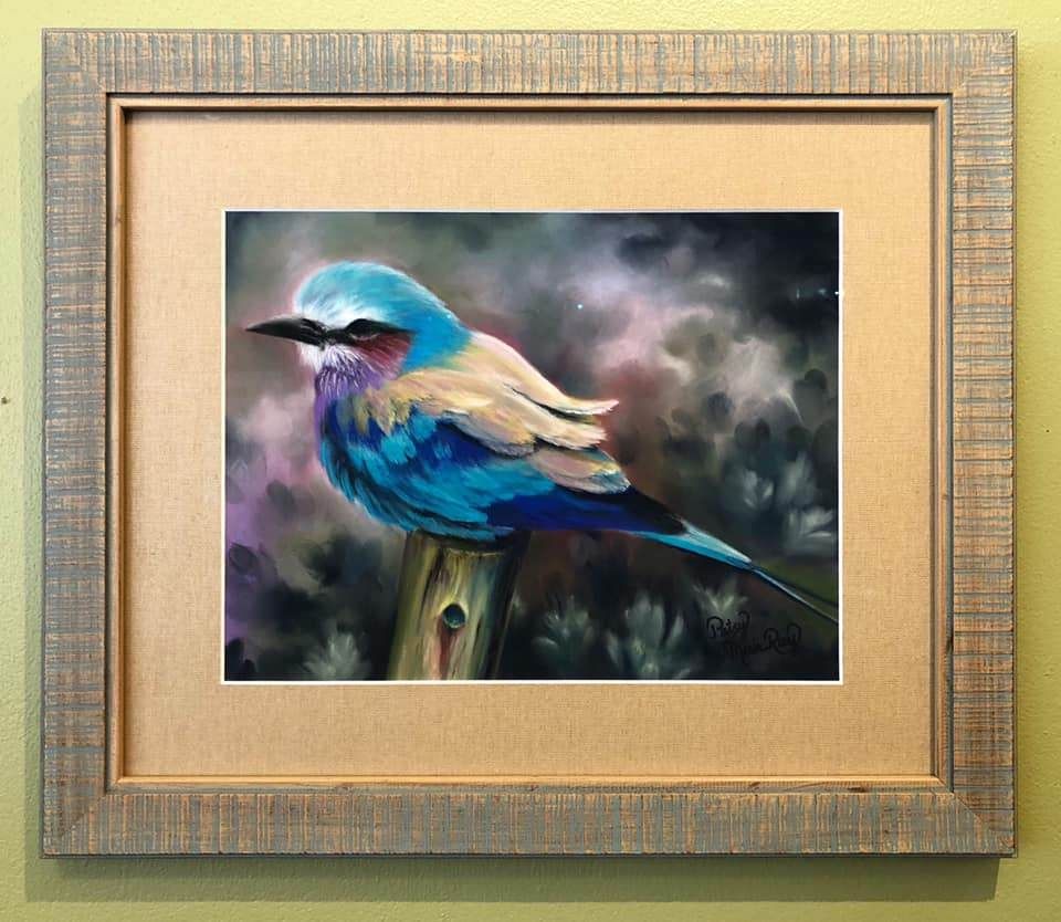 A framed painting of a blue bird perched on a tree branch.