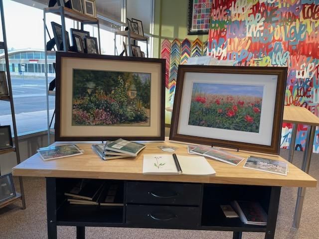 Two framed paintings are on a wooden table