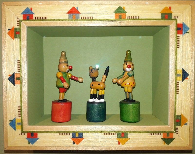 Three wooden toys are displayed in a wooden frame