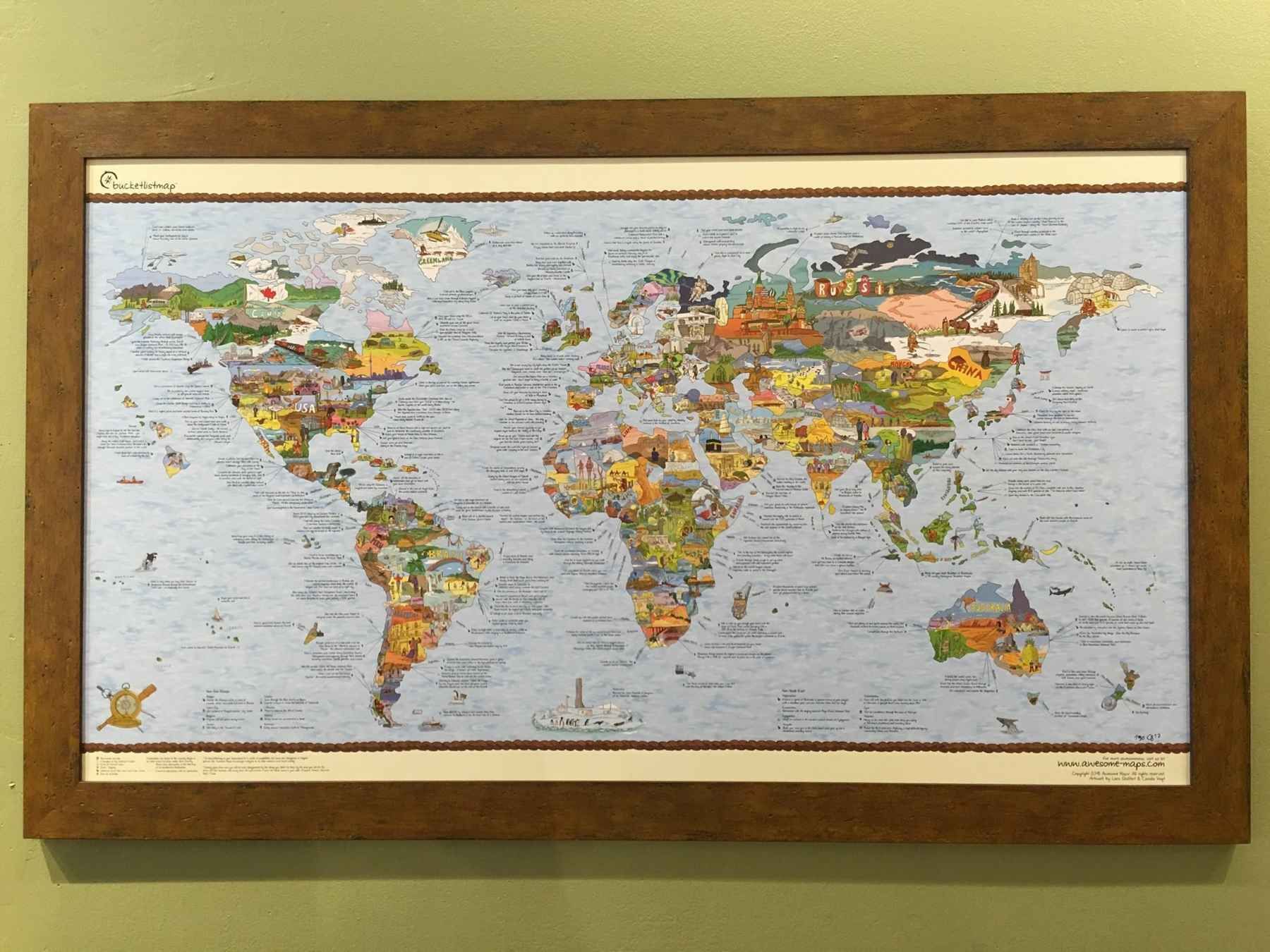A framed map of the world is hanging on a green wall.