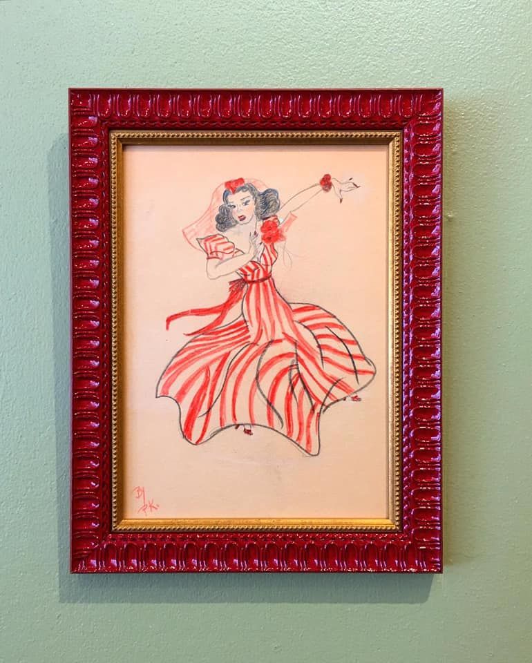 A framed picture of a woman in a red and white striped dress