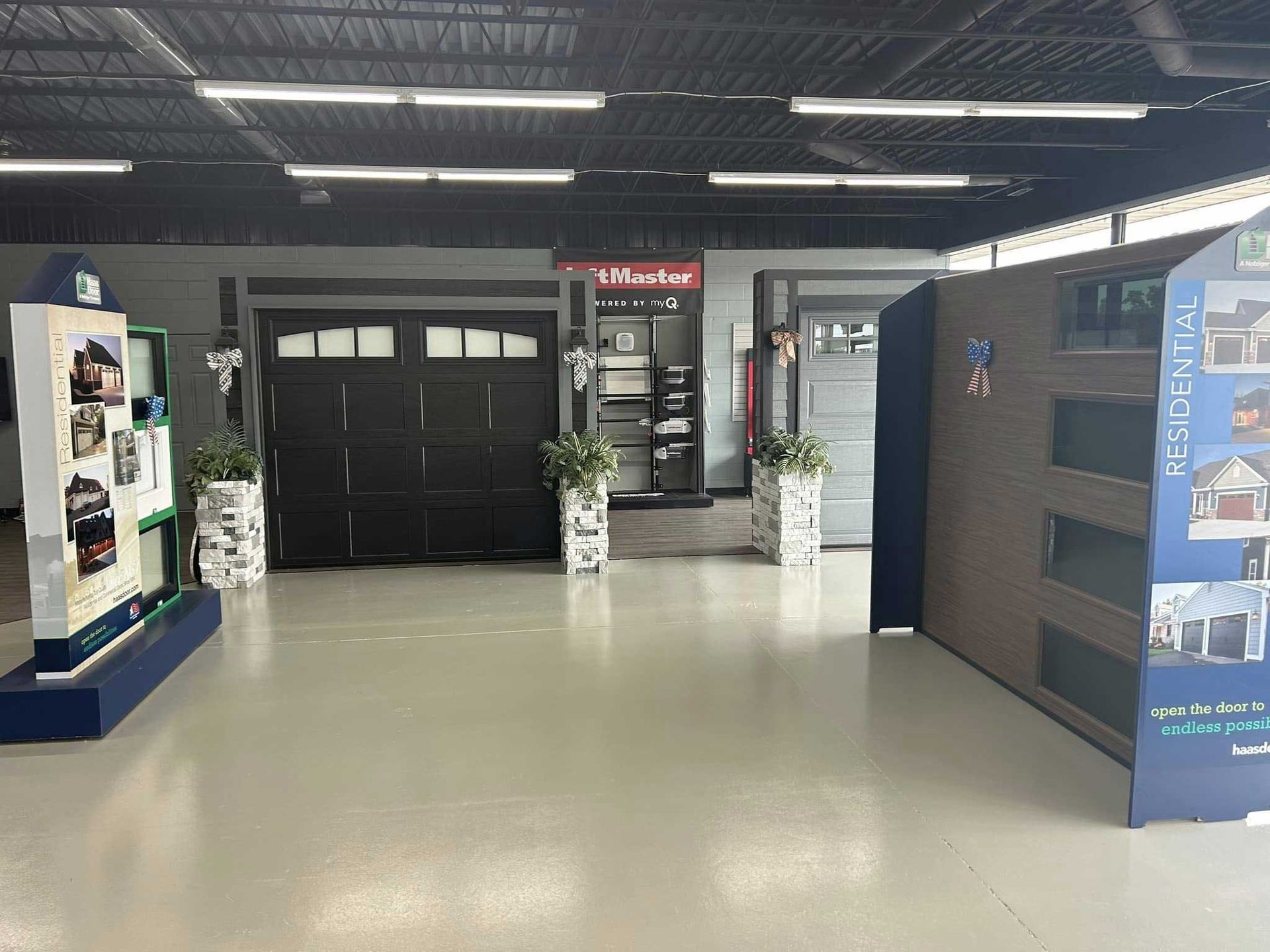 A garage door showroom with dark door display, informational displays, and light flooring.