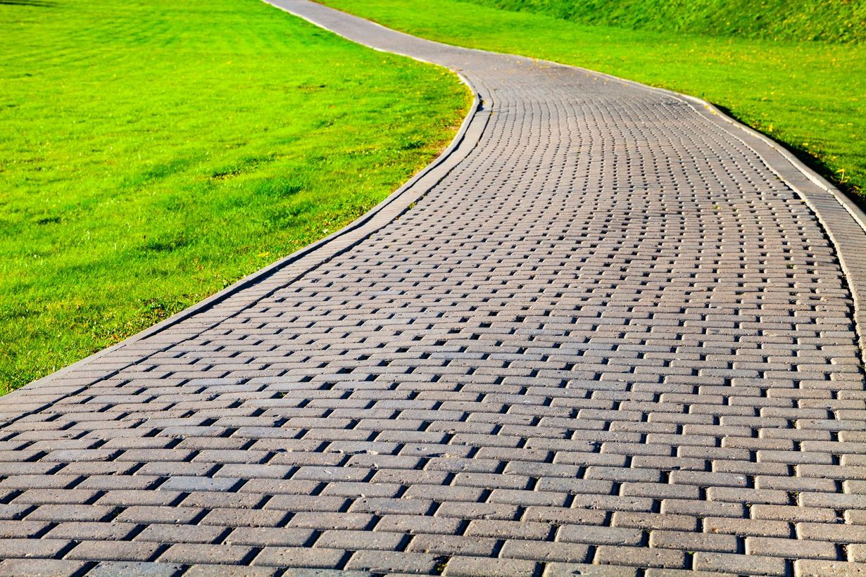 Curving brick pathway through bright green grass