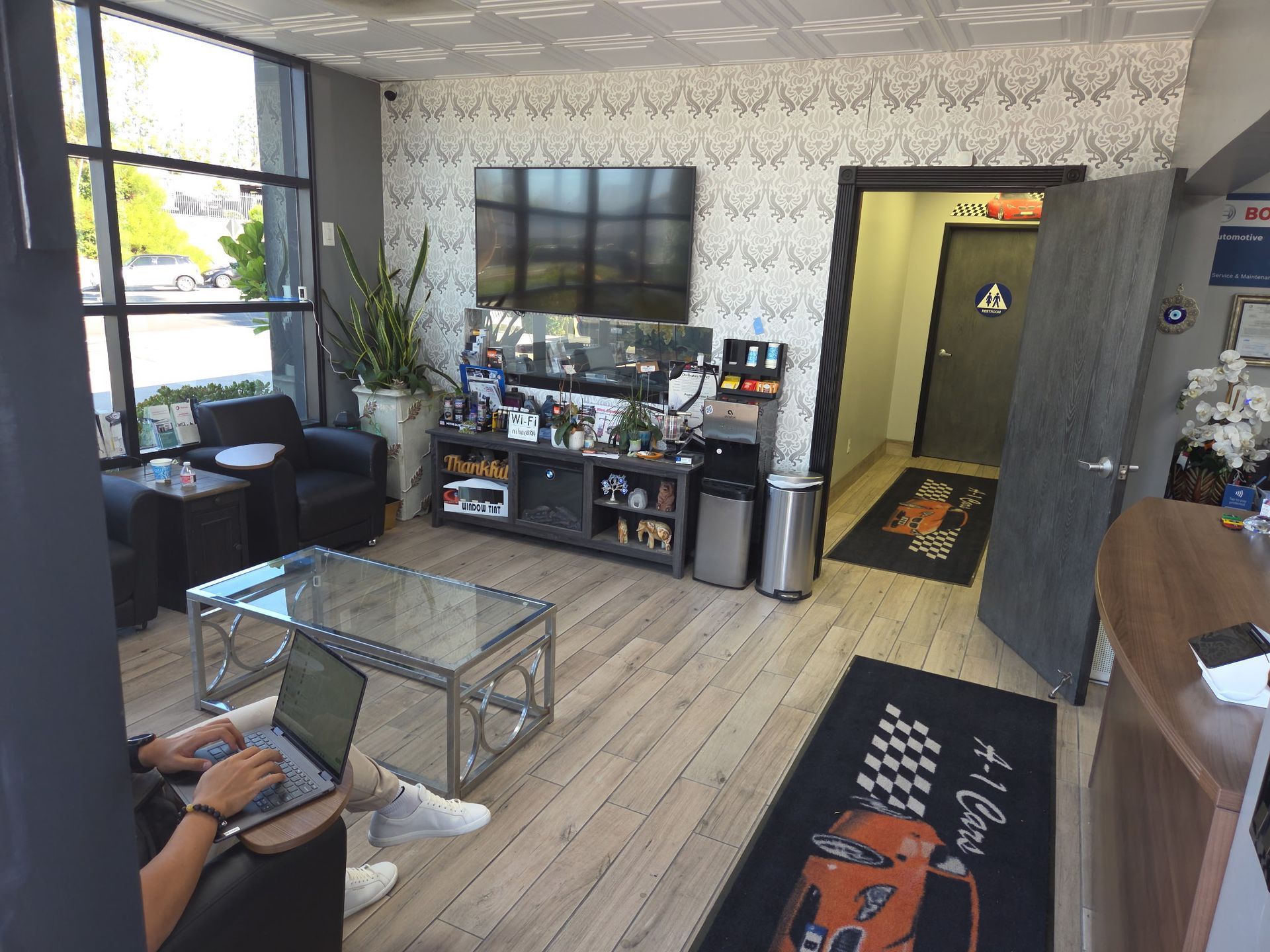 Lobby with person using a laptop. Includes a waiting area, TV, and door to a restroom.