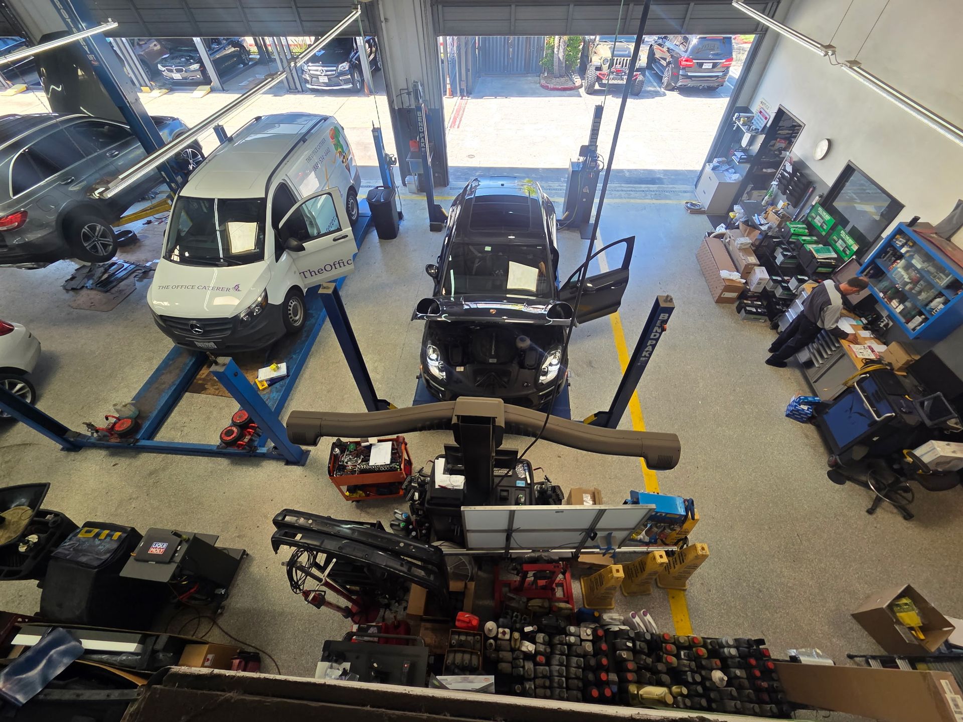 Garage interior with vehicles on lifts, tools, and equipment scattered around.