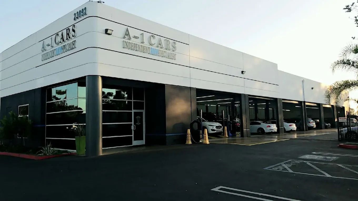 A car wash facility with multiple bays. The building is white and black with cars in the bays.
