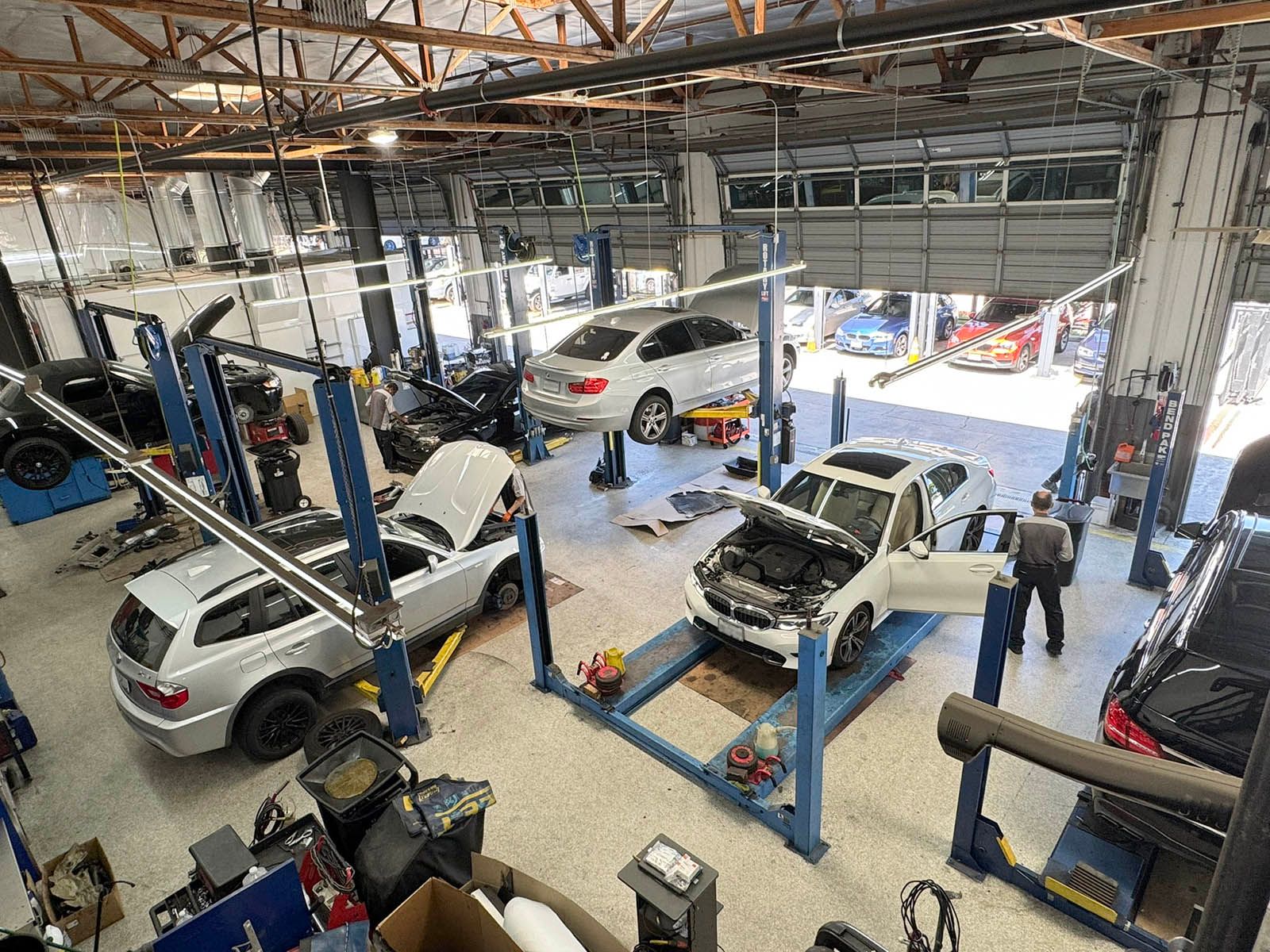 Auto repair shop with several cars on lifts and mechanics working in a bright garage
