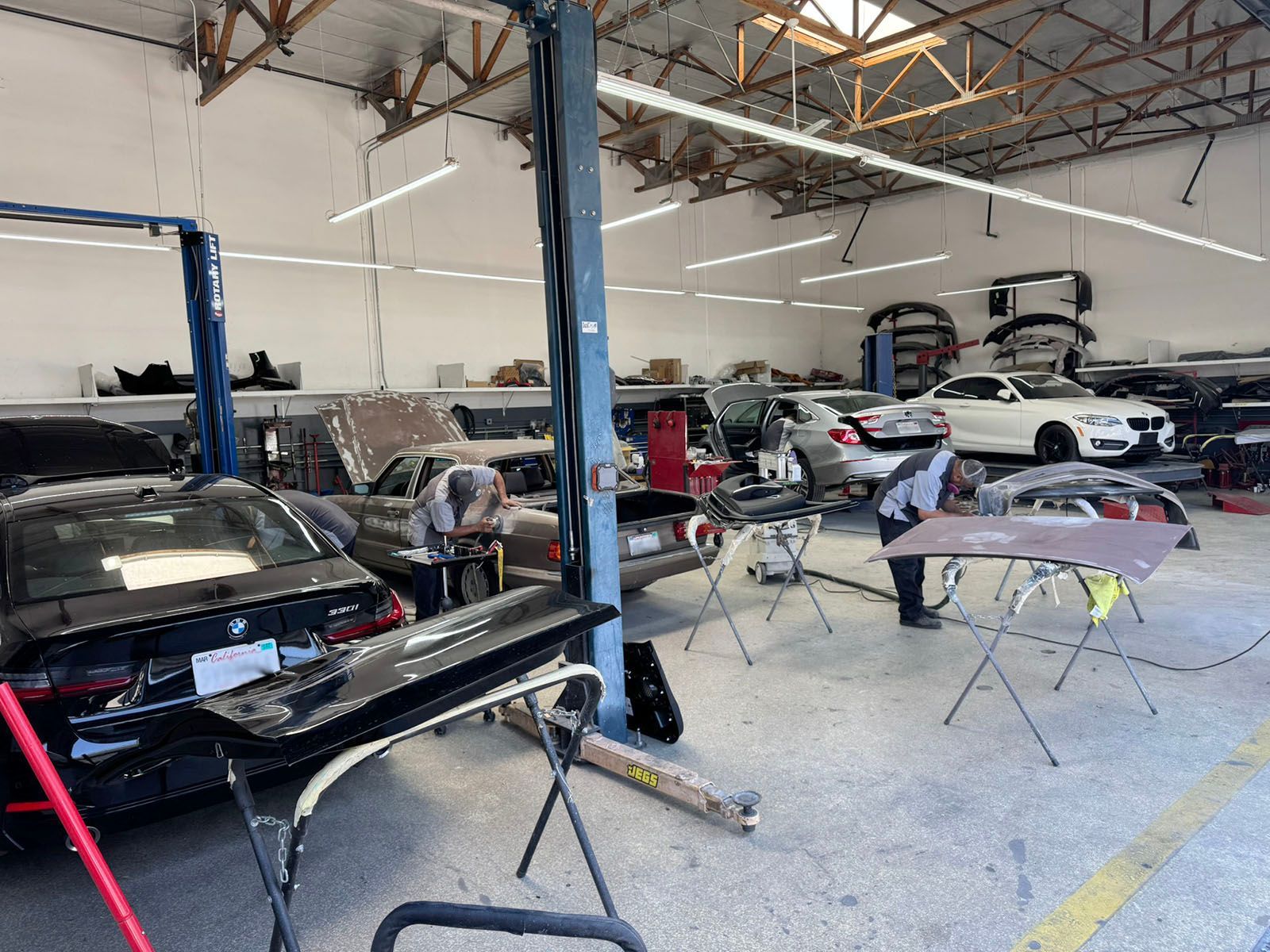 Auto repair shop with several cars, lifts, and mechanics working inside a large garage
