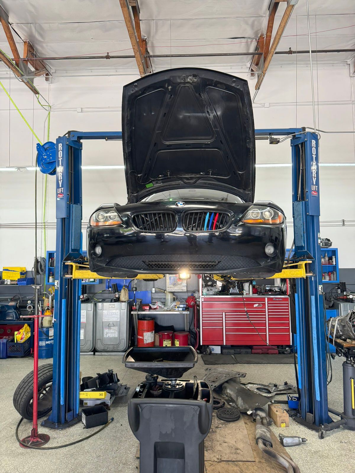 Car lifted in auto repair shop with hood open and tools organized beneath it