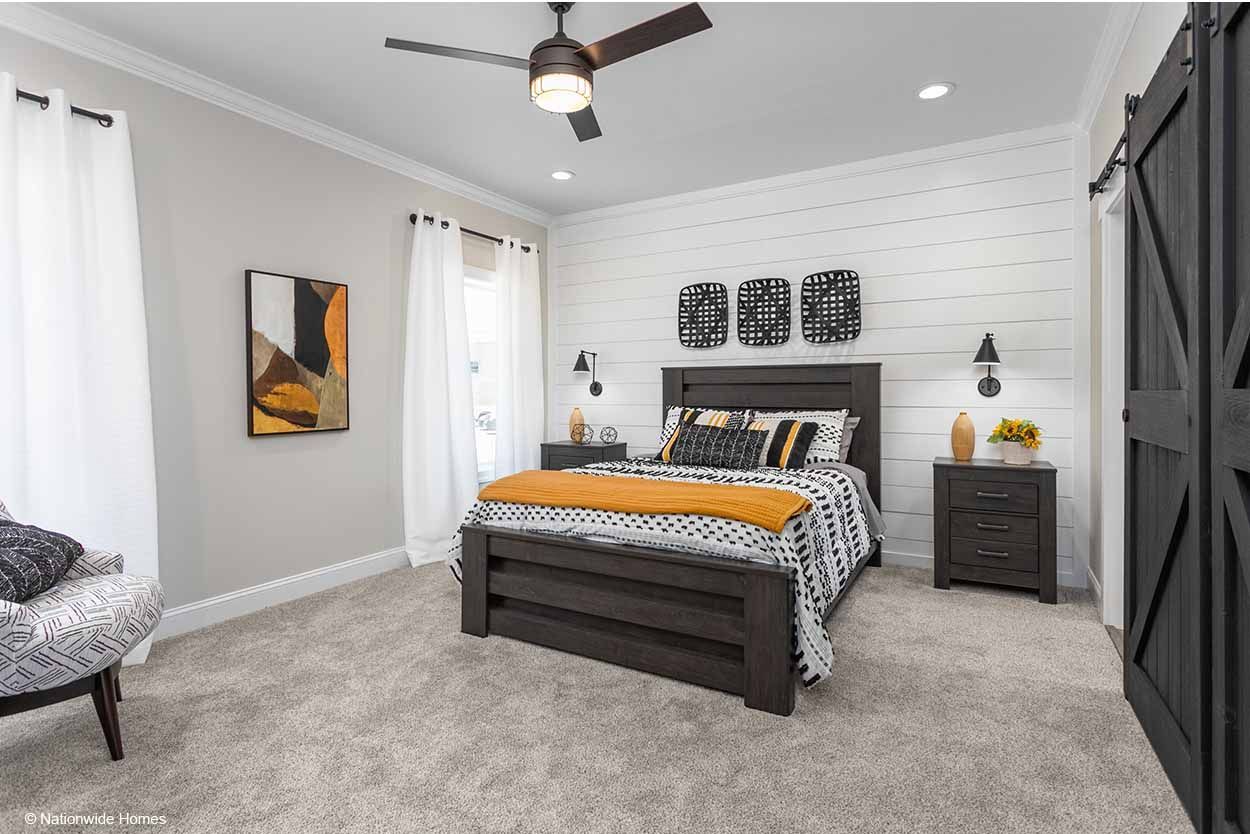 A bedroom with a bed, nightstands, a ceiling fan, and a sliding barn door.