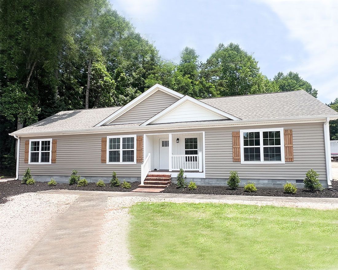 A house with a brown roof and white trim is sitting on top of a lush green field.