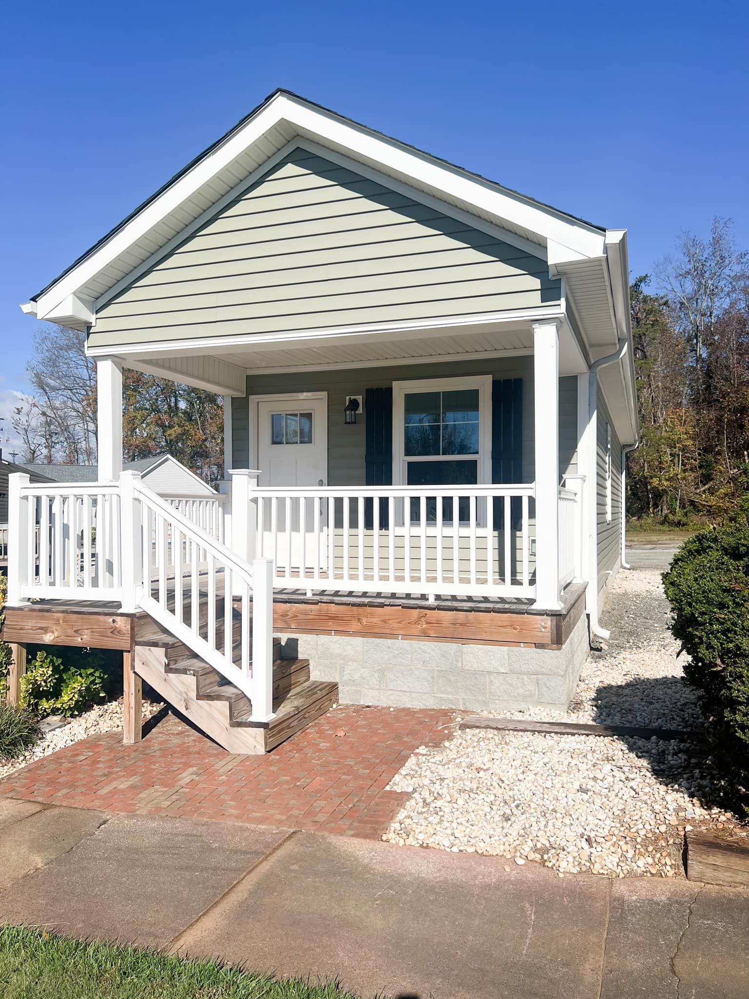 A small house with a white porch and stairs.