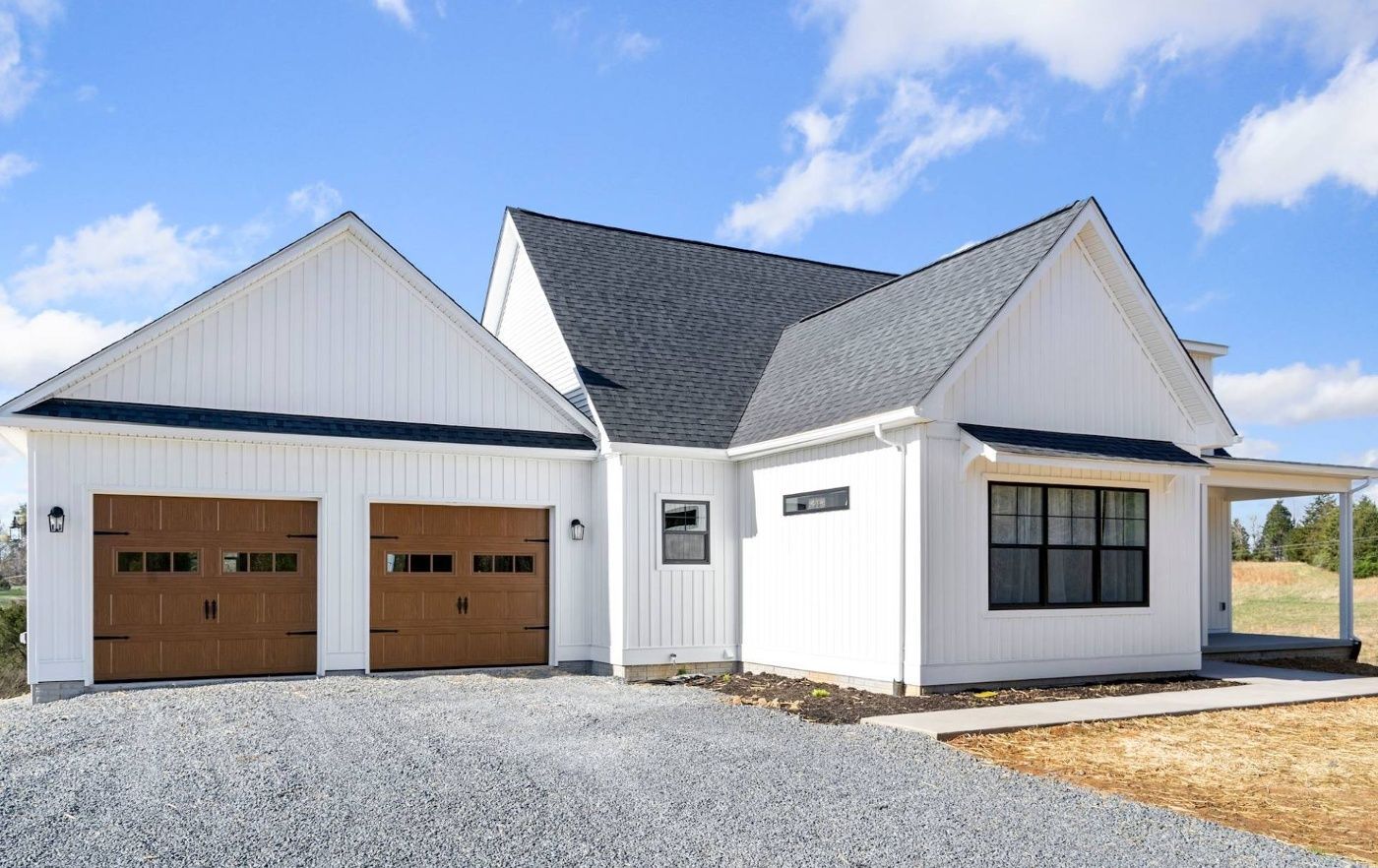 A white house with two garage doors and a gray roof.