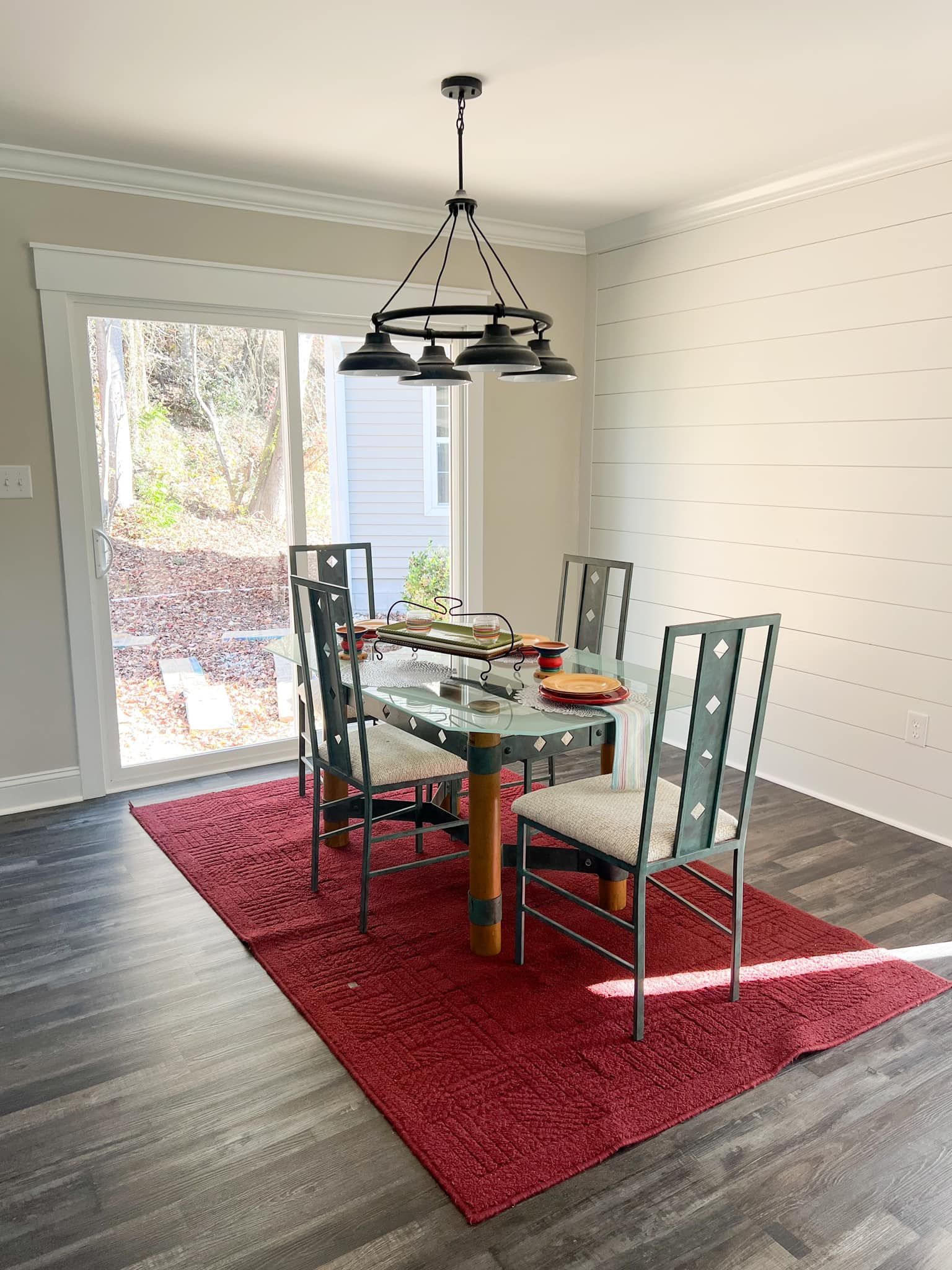 A dining room with a table and chairs and a red rug.