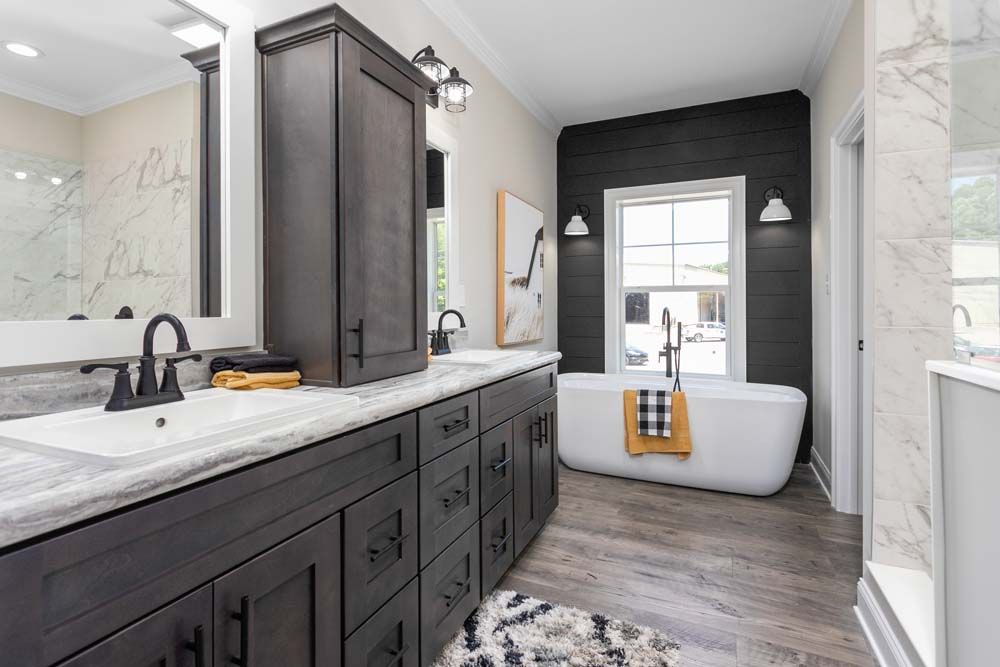 A bathroom with two sinks, a tub, a mirror and a window.