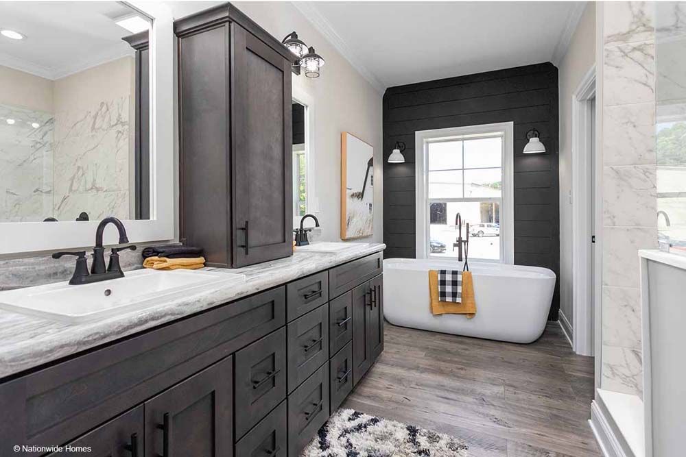 A bathroom with two sinks, a tub, a mirror and a window.