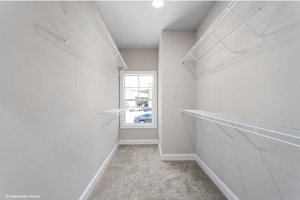 A walk in closet with lots of shelves and a window.