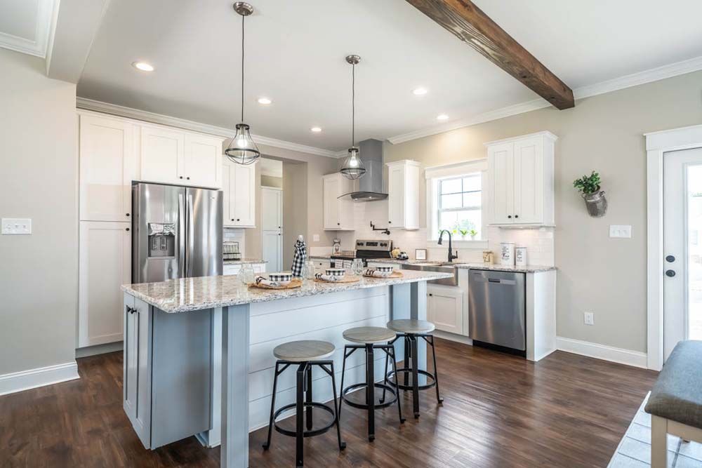 A kitchen with white cabinets, stainless steel appliances, a large island and stools.