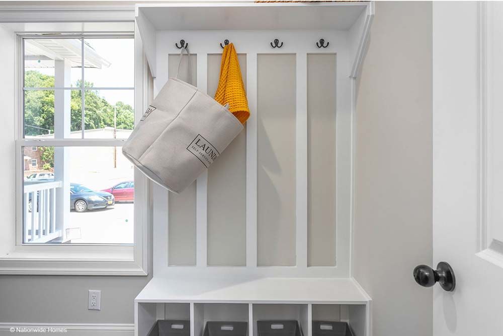 A white coat rack with a yellow towel hanging from it.