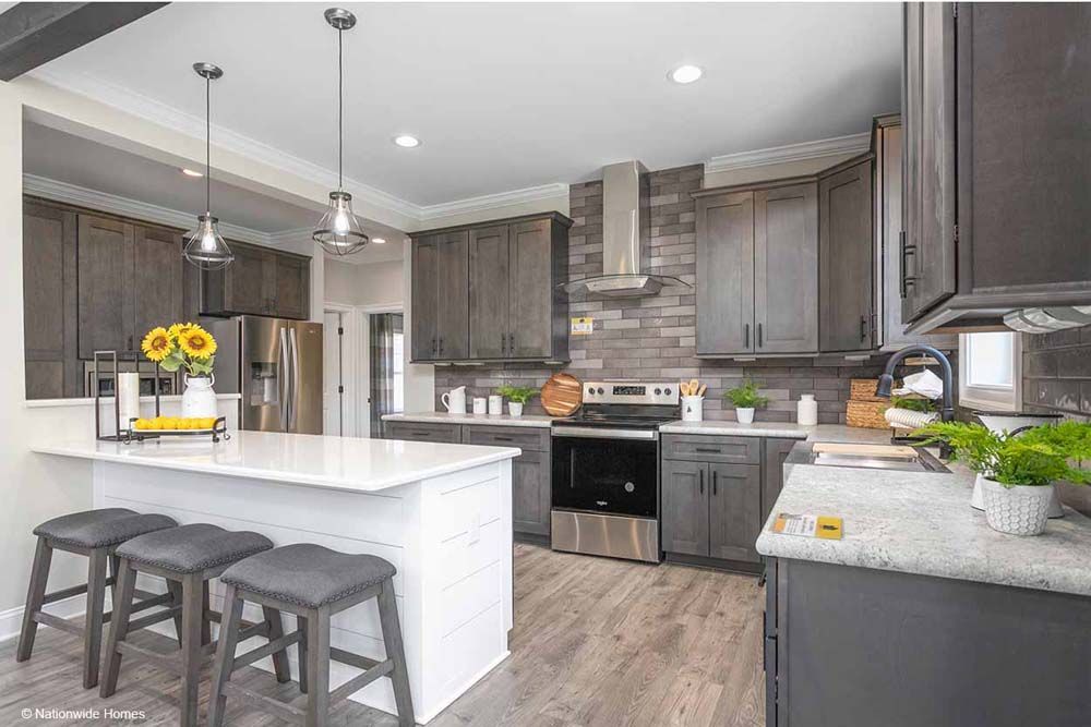 A kitchen in a mobile home with stainless steel appliances and gray cabinets.