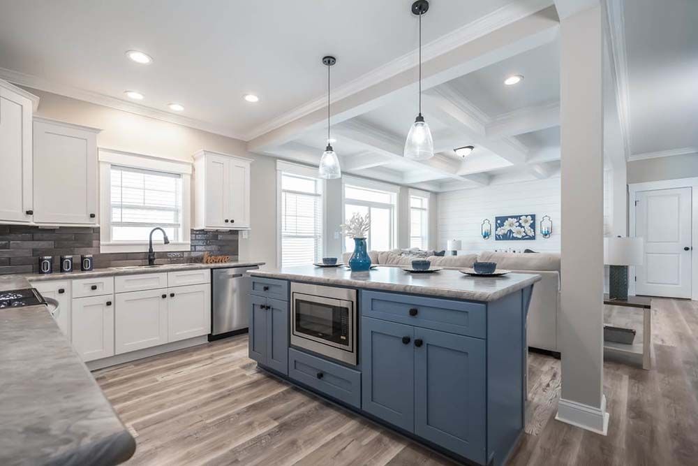 A kitchen with blue cabinets and white cabinets and a large island in the middle.