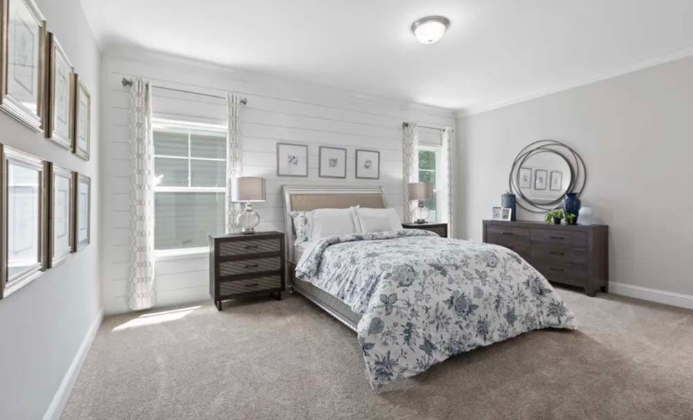 A bedroom with a bed, dresser, nightstand and window.