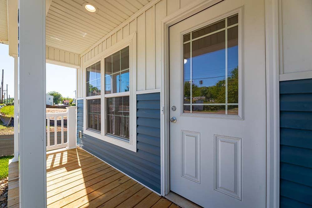 A bedroom with a bed, dresser, and two windows.