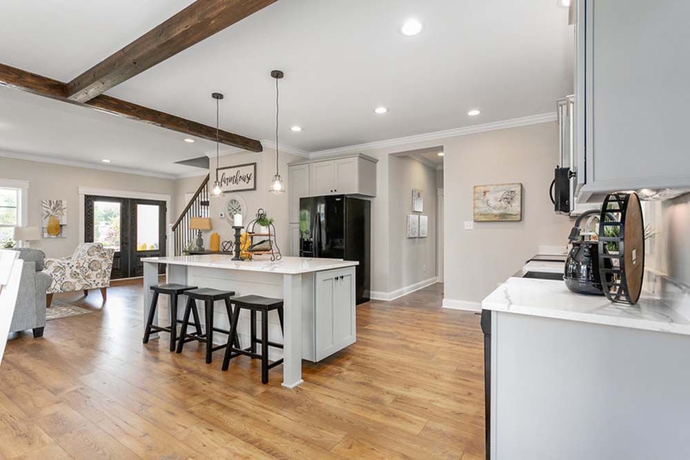 A kitchen with a large island, stools and a refrigerator.