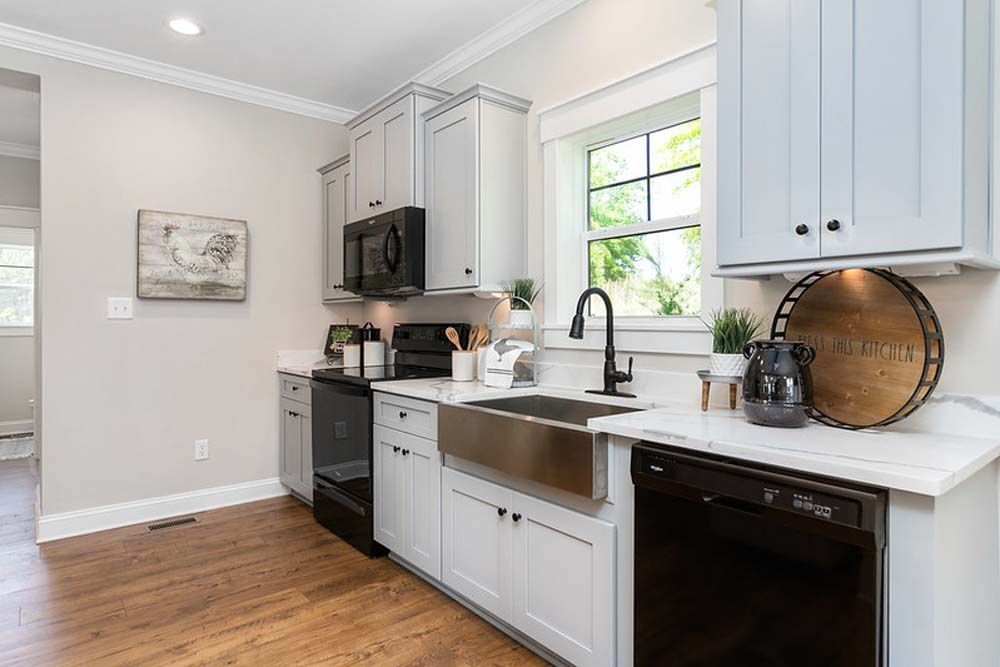 A kitchen with white cabinets, stainless steel appliances, a sink, and a window.