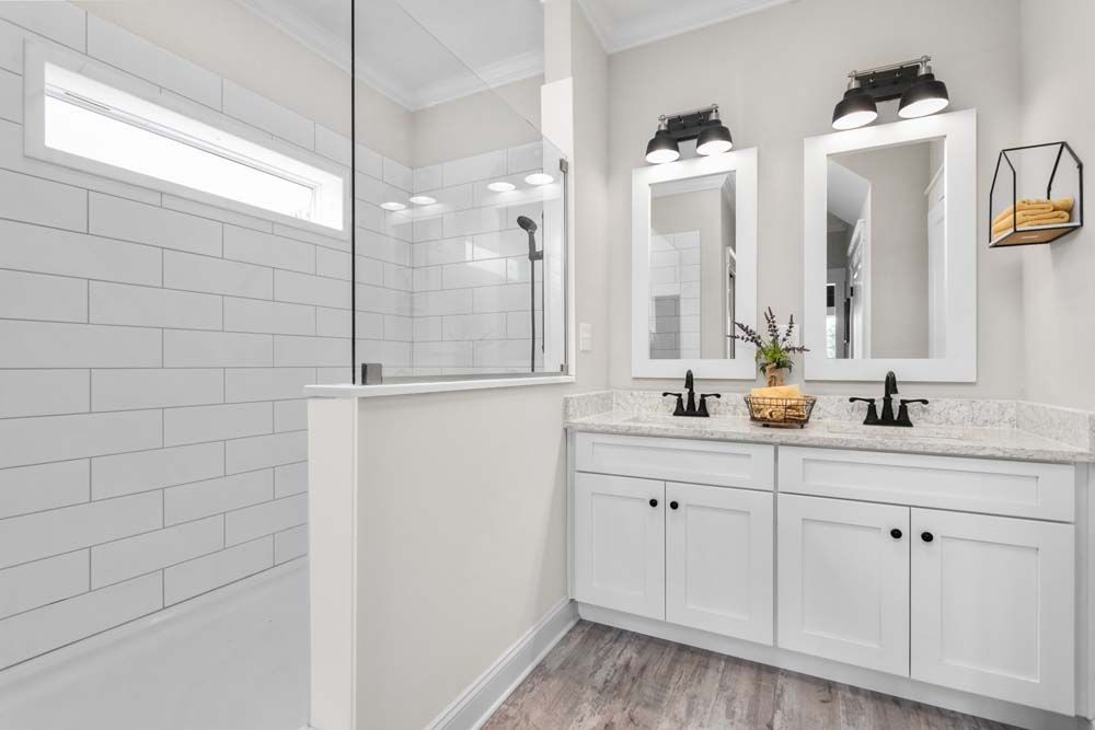 A bathroom with two sinks and a walk in shower.