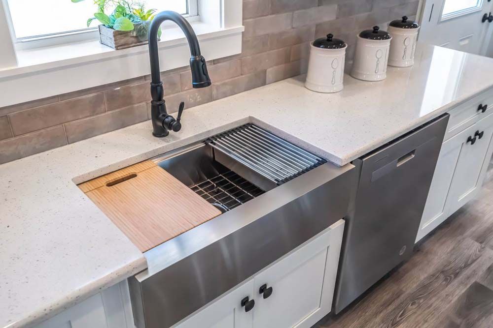 A kitchen with a large stainless steel sink and a dishwasher.
