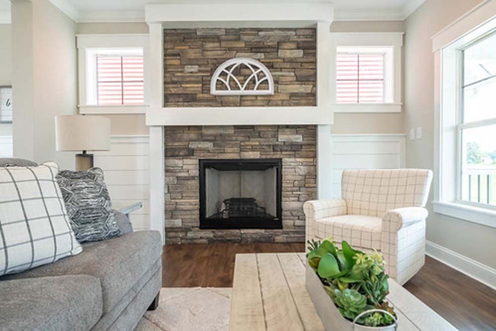 A living room with a fireplace, couch, chair and coffee table.