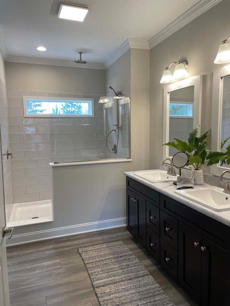 A bathroom with two sinks and a walk in shower.