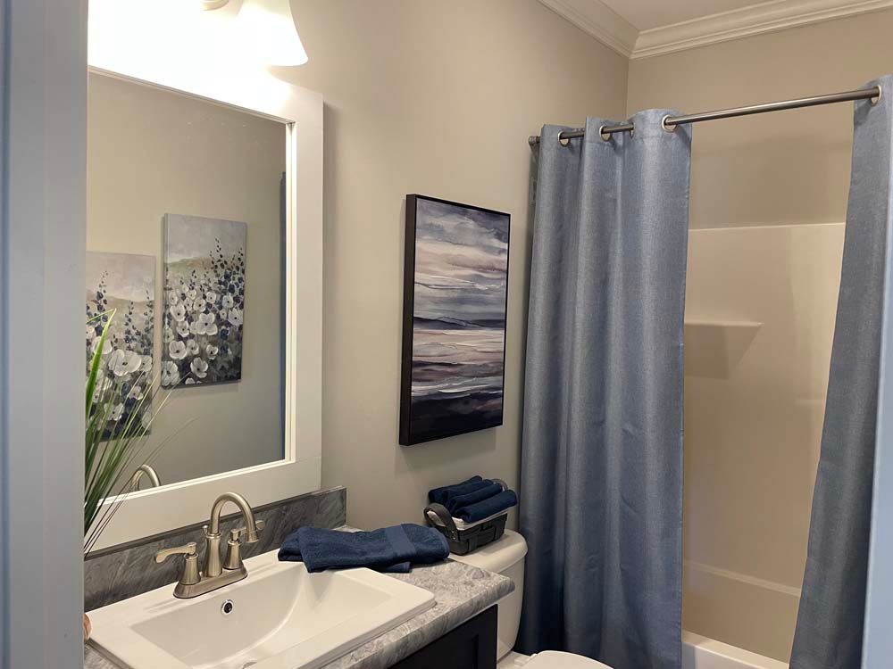 A bathroom with a sink, toilet, shower and mirror.