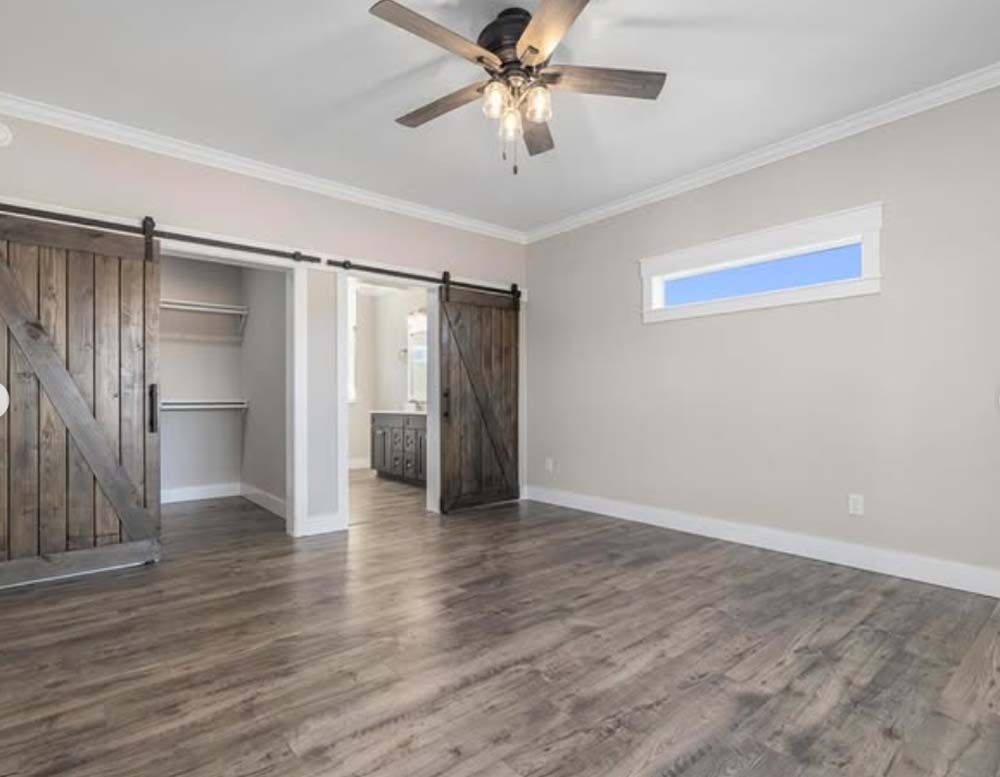 A bedroom with sliding barn doors and a ceiling fan.