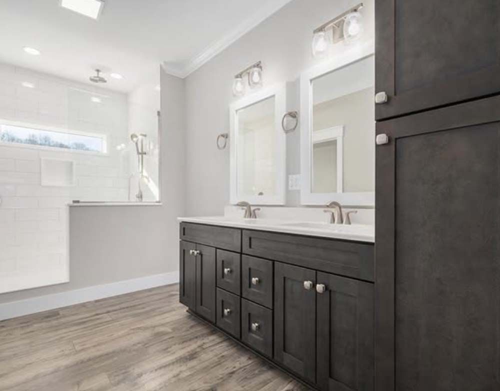 A bathroom with two sinks, two mirrors and a walk in shower.