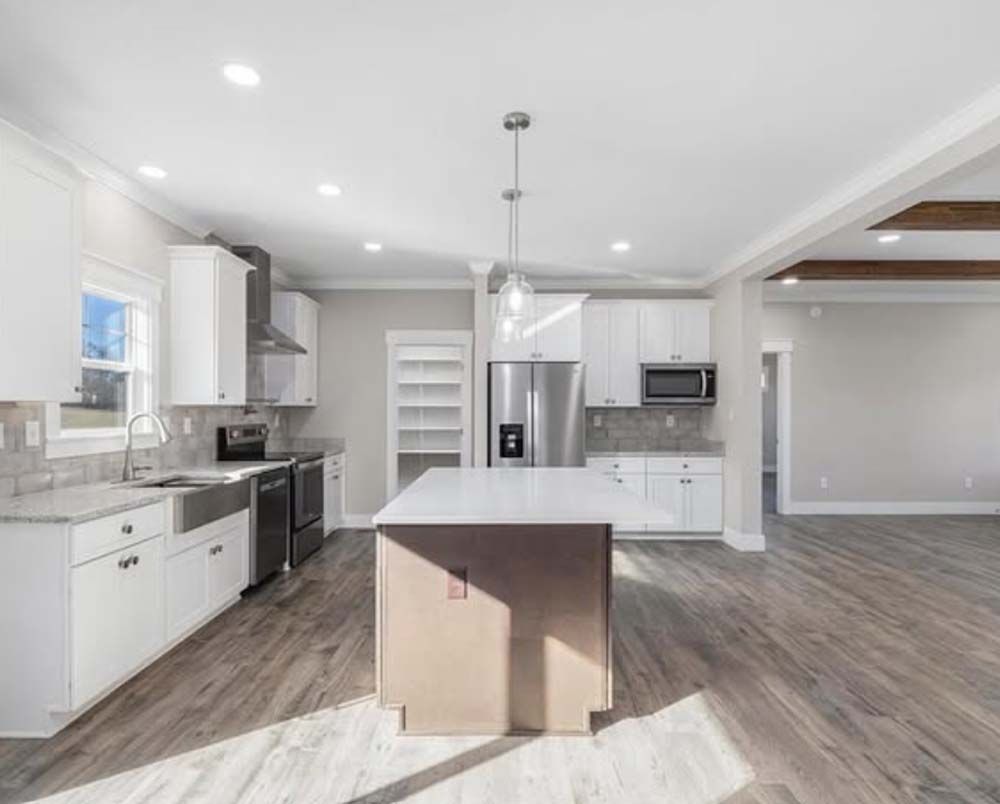 A kitchen with white cabinets, stainless steel appliances, and a large island.