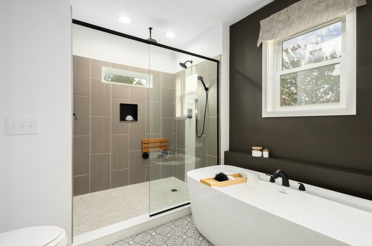 A bathroom with a bathtub, shower and window.