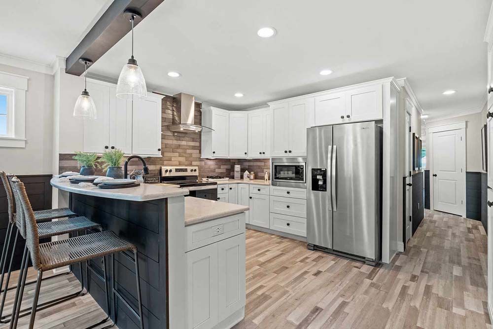A kitchen with stainless steel appliances, cabinets, hardwood floors and a large island.