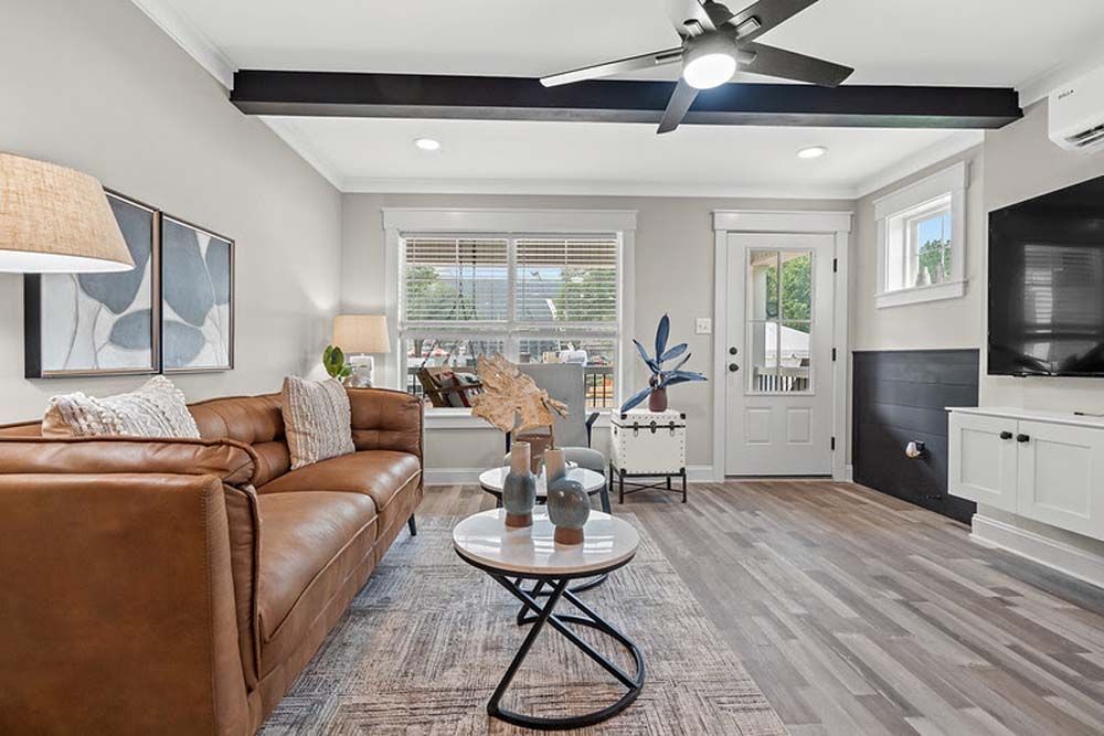 A living room with a brown couch, a coffee table, and a ceiling fan.