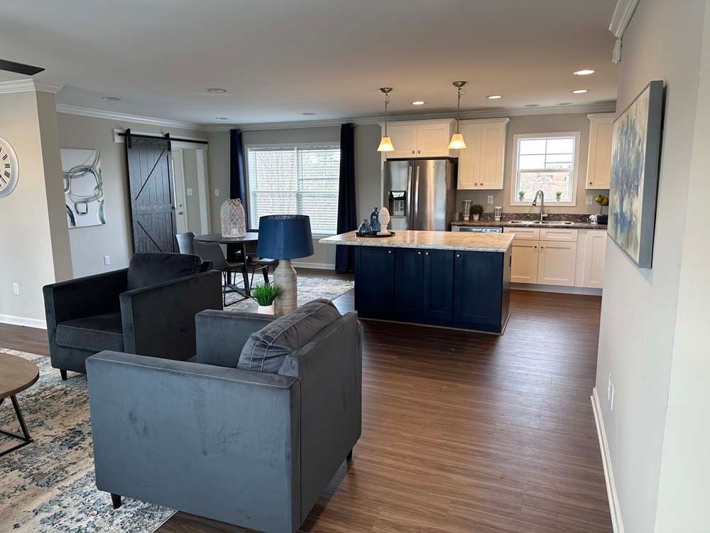 A living room with a couch, chairs, and a kitchen.