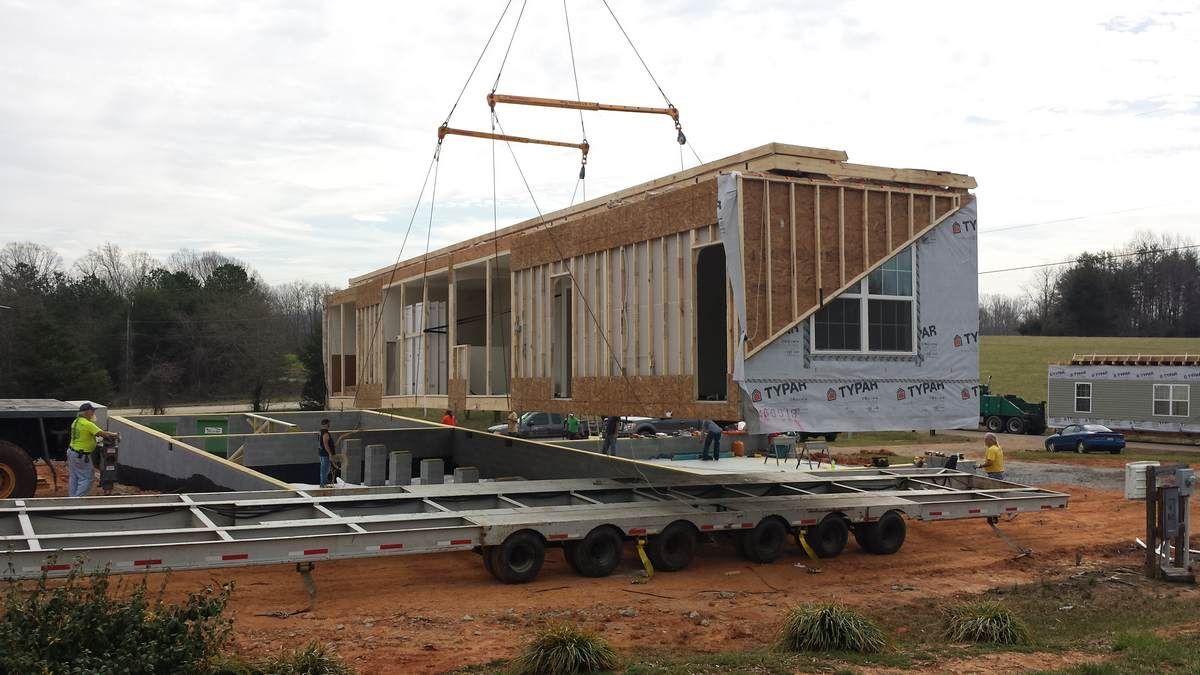 A house is being built on a trailer on a construction site.