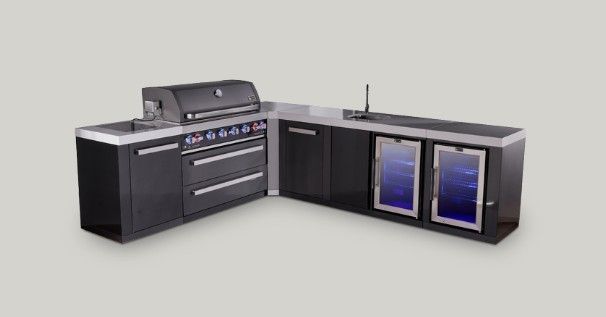 Outdoor kitchen with black cabinets, stainless grill, and blue-lit beverage fridges