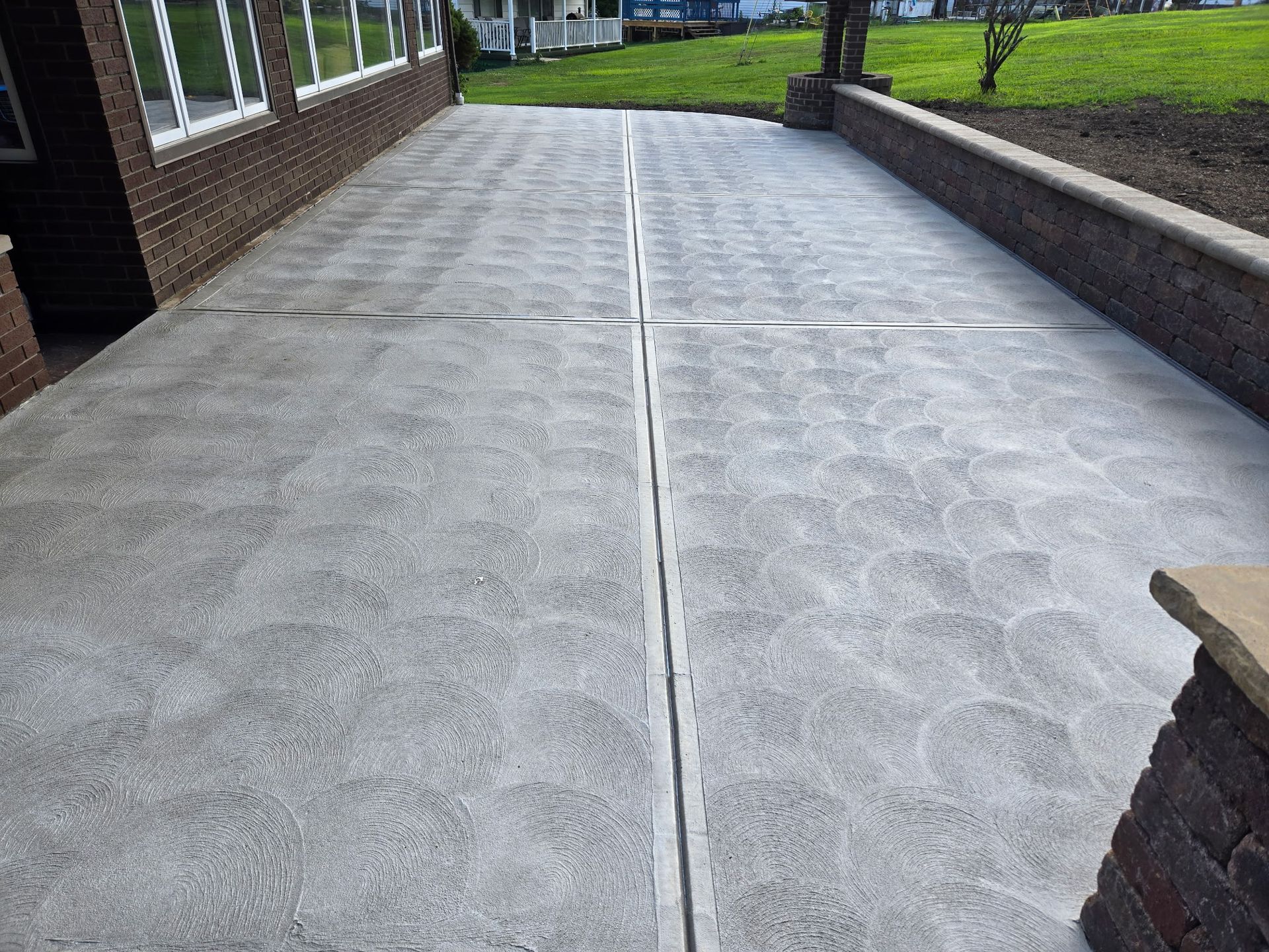 Concrete walkway beside a brick building, with windows and low walls on both sides.